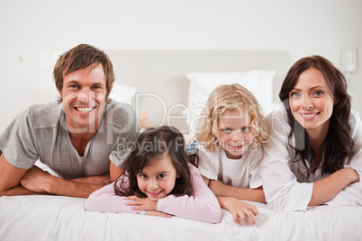 Smiling family lying in a bed