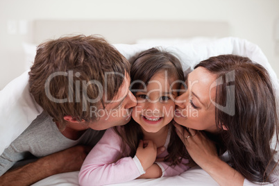 Parents kissing their daughter