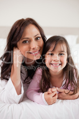 Portrait of a mother and her daughter lying on a bed