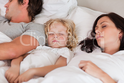 Boy sleeping between his parents