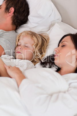 Portrait of a boy sleeping between his parents