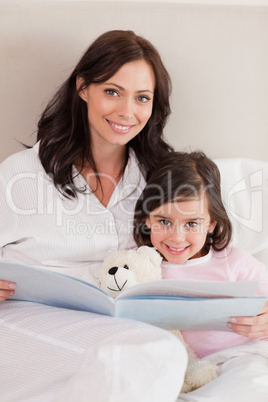 Portrait of a happy mother reading a story to her daughter