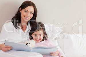 Happy mother reading a story to her daughter
