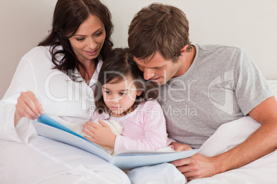 Parents reading a story to their daughter