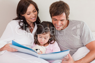 Happy parents reading a story to their daughter