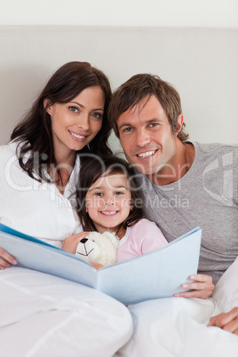 Portrait of parents reading a story to their daughter