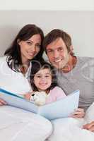 Portrait of parents reading a story to their daughter