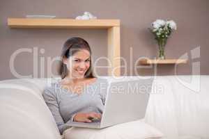 Smiling woman with her notebook on the sofa
