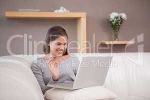 Cheerful woman with her notebook on the sofa