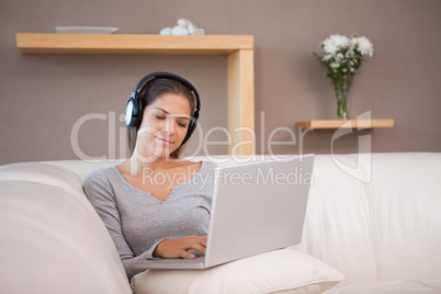 Woman with laptop and headphones on the sofa