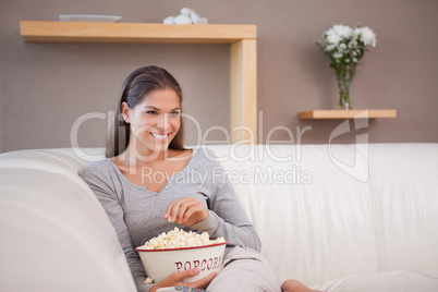 Smiling woman having popcorn while watching a movie