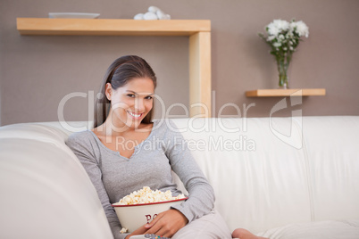 Woman on the sofa watching a movie with a bowl of popcorn