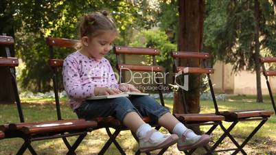 little girl reading a book in park