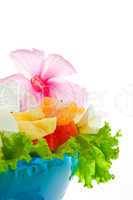 Fruit salad with edible flowers in a blue bowl from ice on white
