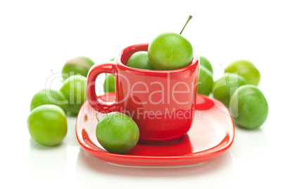 green plum  in the red cup isolated on white