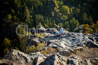 young man using laptop sitting on a rock slope