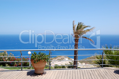 Aegean Sea view area with palm and pot of flowers, Crete, Greece