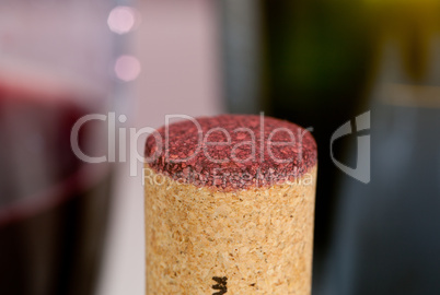 Red wine soaked cork in front of glass