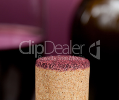 Red wine soaked cork in front of glass