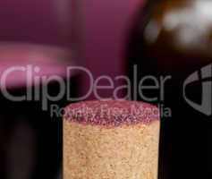 Red wine soaked cork in front of glass