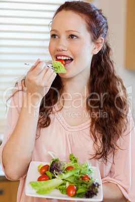 Woman eating salad in the kitchen