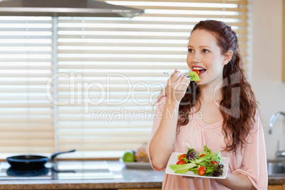 Girl eating some salad in the kitchen