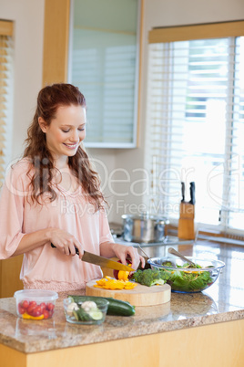 Smiling woman cutting bell pepper