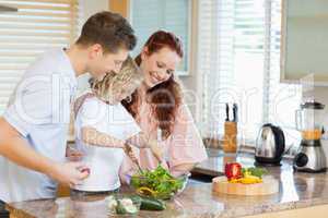 Couple letting their child stir the salad
