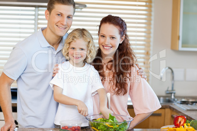 Smiling family preparing salad together