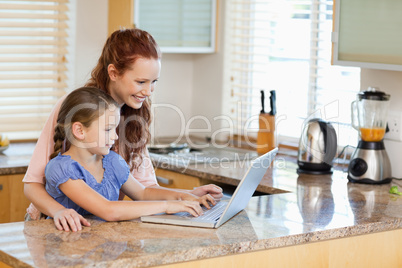 Mother and daughter with laptop in the kitchen