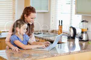 Mother and daughter with laptop in the kitchen