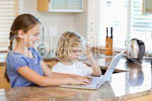 Siblings on the laptop in the kitchen