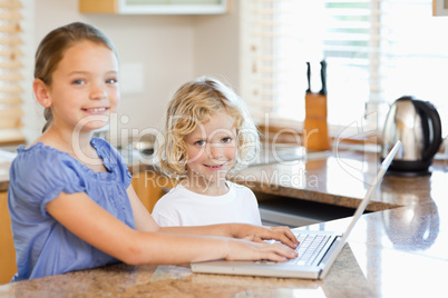 Smiling siblings on the laptop in the kitchen