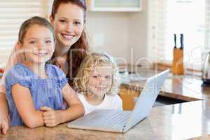 Mother with children on them laptop in the kitchen