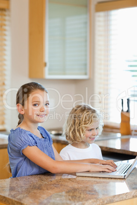 Brother and sister with laptop in the kitchen