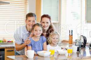 Family together with breakfast standing behind the kitchen count
