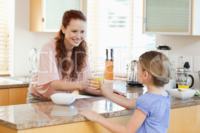 Mother giving her daughter orange juice