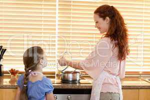 Mother showing her daughter what shes cooking