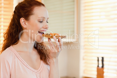 Side view of woman biting into slice of bread