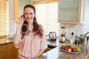 Woman with cellphone behind the kitchen counter