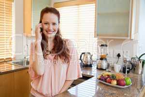 Smiling woman talking on the phone in the kitchen