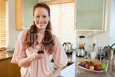 Woman holding her cellphone in the kitchen