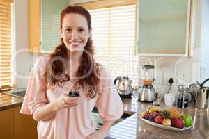 Woman holding her cellphone in the kitchen