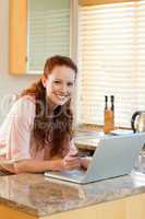 Smiling woman in the kitchen booking holiday online