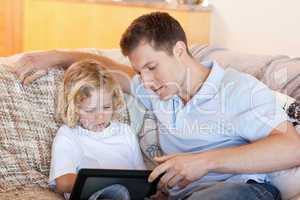 Father and son using tablet on the sofa