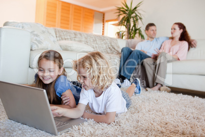 Siblings using laptop in the living room