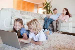 Siblings using laptop in the living room