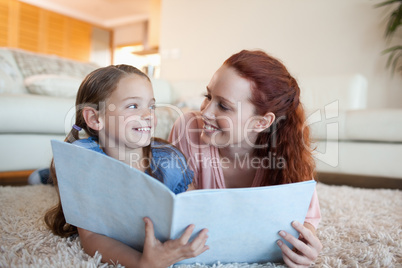 Mother and daughter with periodical on the floor