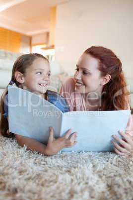 Mother and daughter on the floor looking at magazine