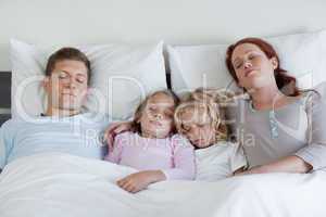 Family sleeping in the bed together